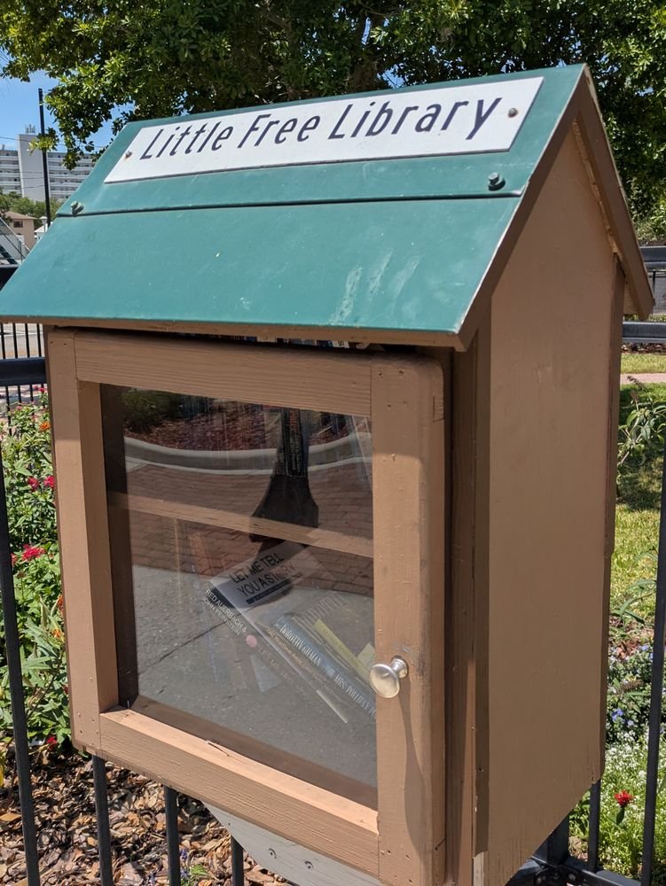 This Little Free Library is located on the Sebring Circle adjacent to the Circle Theater. It faces the circle and is easy to access on foot. Painted brown with a green roof, it has a single door with a clear panel. Inside, two shelves where all kinds of books can be found.